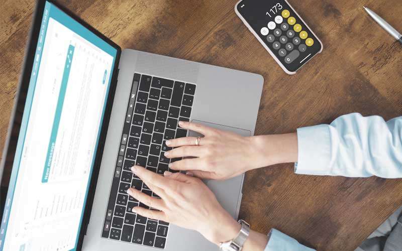 Bild zur Berechnung eines Wasserschadens. Laptop von oben mit Frauen Händen, die tippen: Anhand dieser Beispielrechnung zeigen wir Ihnen, wie eine erfolgreiche Schadensbegleitung durch WDS aussehen kann.