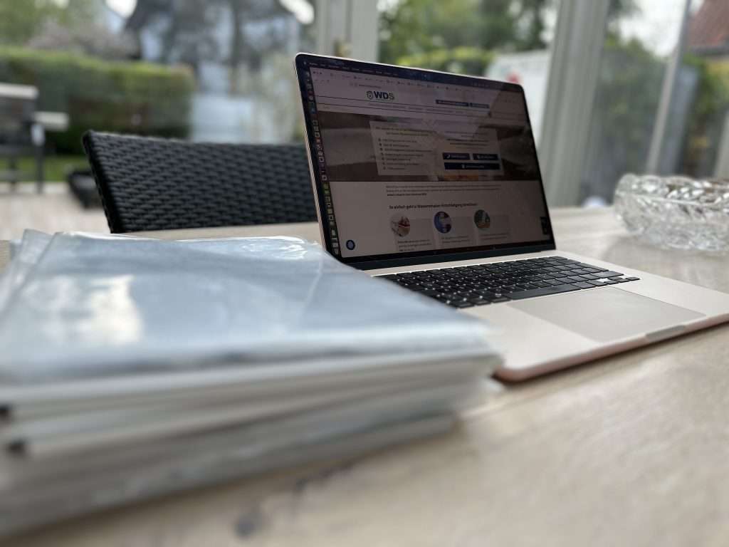 Versicherungspolicen verstehen – Wie lesen Sie die Policen von Ihrer Versicherung richtig? Laptop mit Wasserschadenshilfe Website geöffnet neben vielen Akten und Papieren