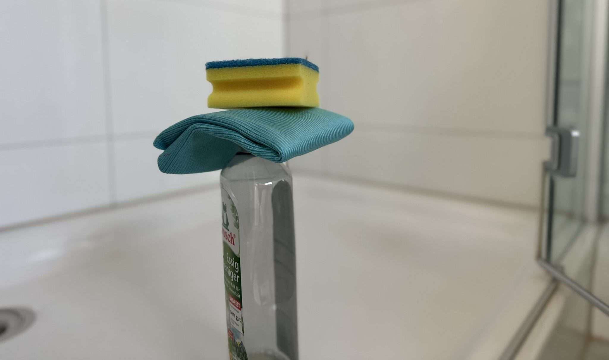 Silikonfugen-IMG_6004-scaled-e1742573692186 Wie pflegt man Silikonfugen richtig und beugt Wasserschaden vor? Bild von Essigreiniger und Schwämmen in einer weißen Dusche